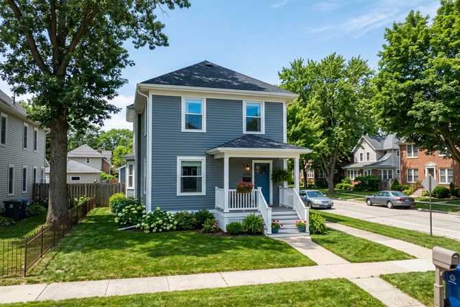 Freshly painted two-story house with white trim on a tree-lined DeKalb street